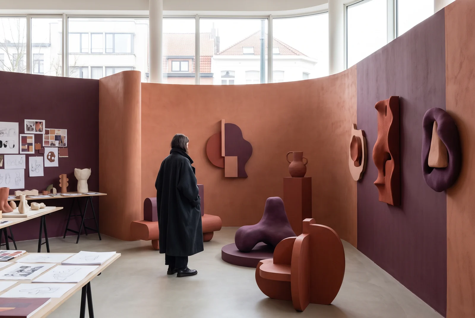 Bezoeker in een interieur met gebogen terracotta wanden en kleurstudies